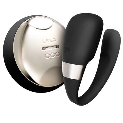 Dispositif noir LELO Tiani 3 en forme de U, placé devant sa télécommande ronde métallisée