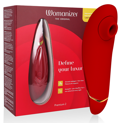 Womanizer Premium 2 bordeaux devant sa boîte rouge, embout rond orienté à droite et liseré doré