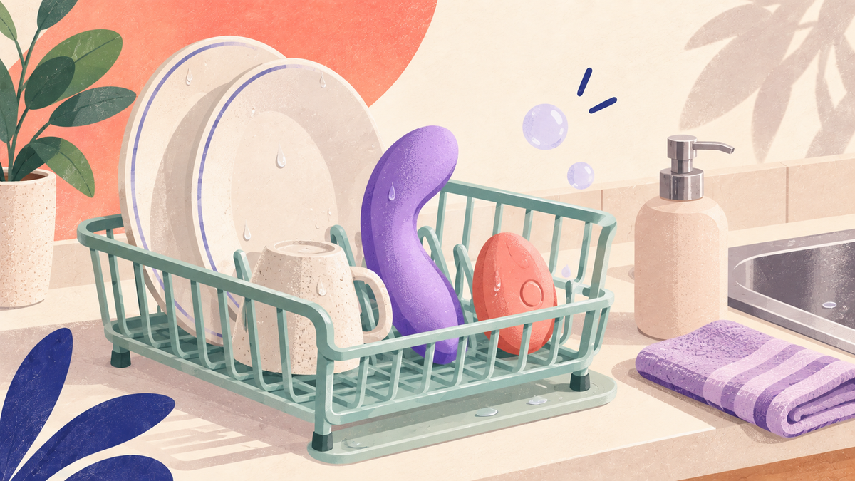 Illustration : deux sextoys, l'un violet et l'autre corail, sèchent sur un égouttoir à vaisselle à côté d'un savon et d'une serviette
